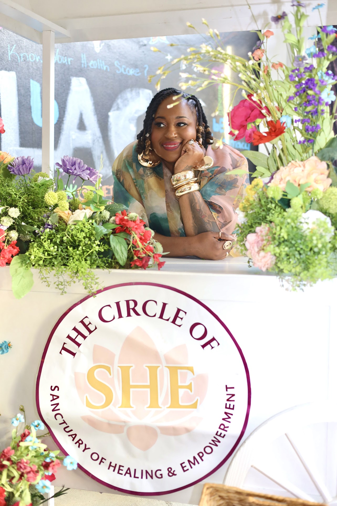 Host posing at the floral cart with Circle of SHE banner