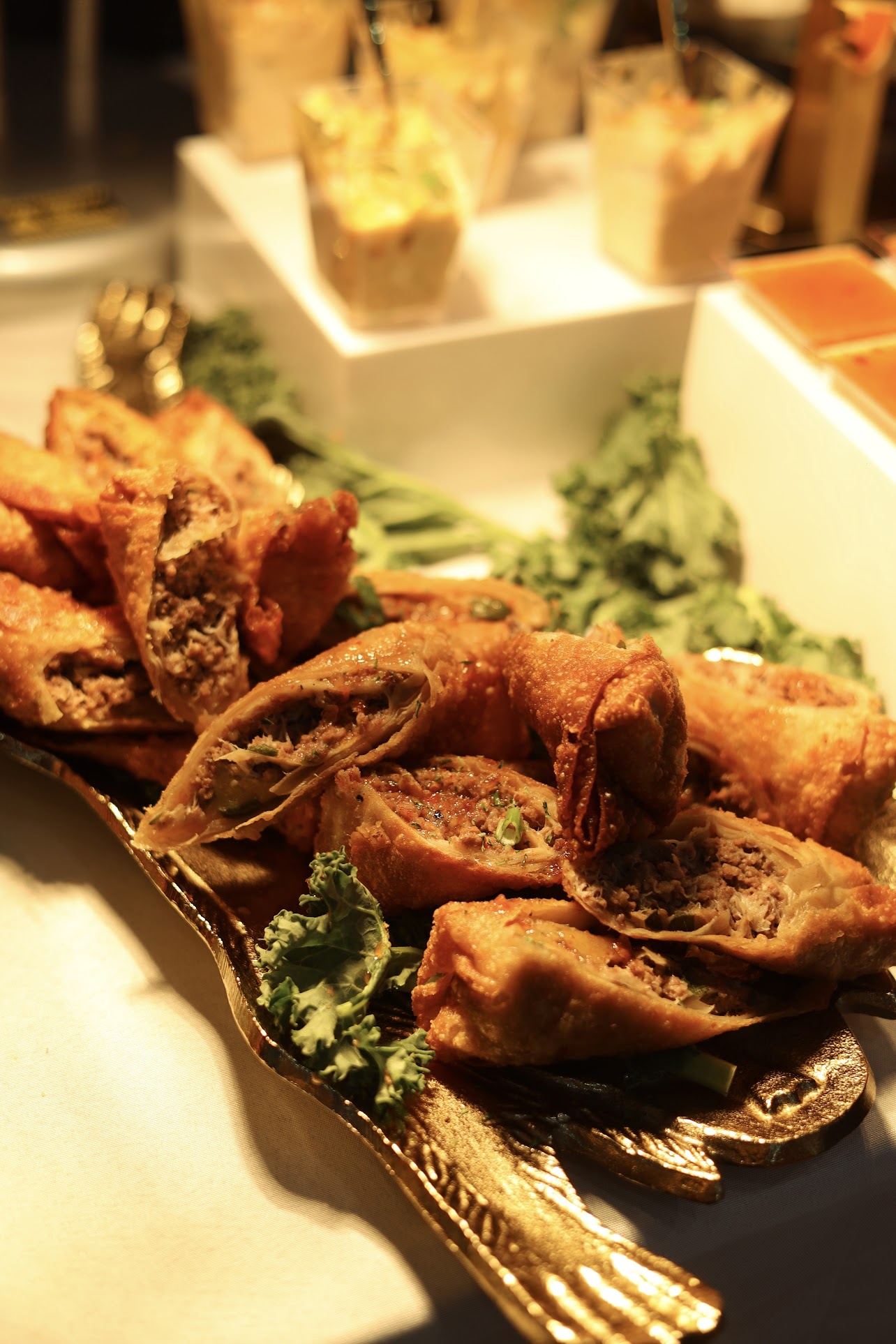 Plated egg rolls and appetizer shooters on a gold tray