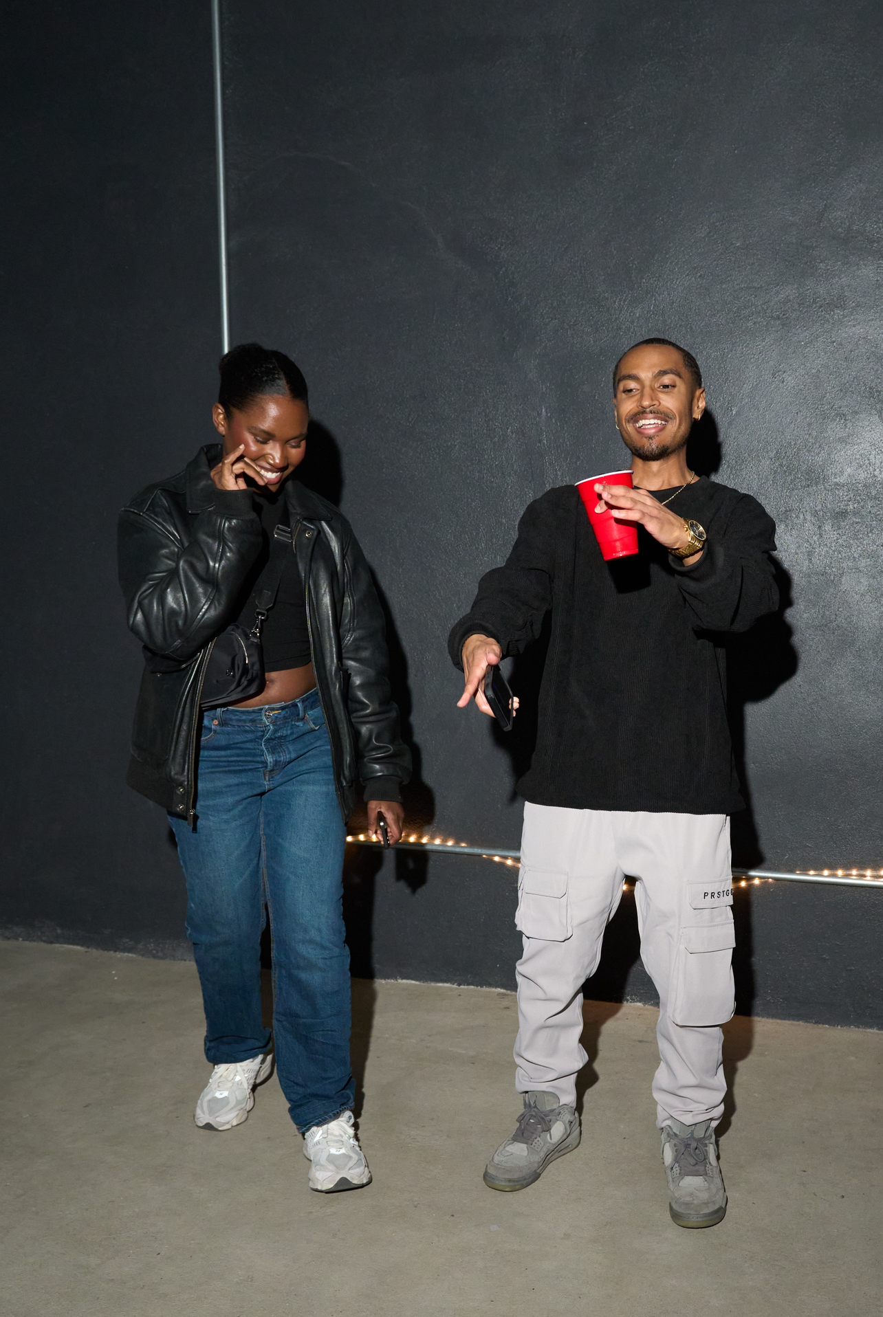 Two guests smiling and chatting against a dark gallery wall